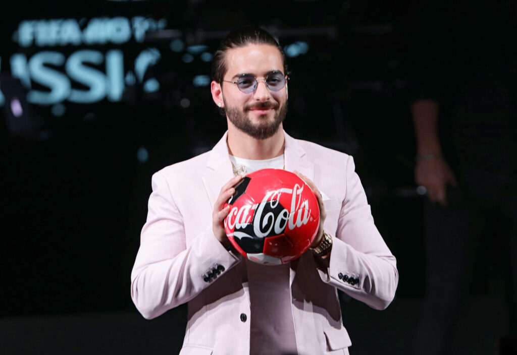 Maluma holding Coca-Cola soccer ball in front of FIFA World Cup backdrop stylish rapper singer Wallpaper