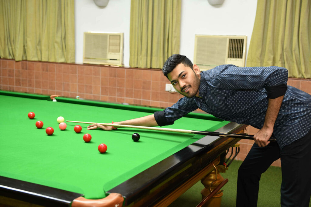 Man aiming pool stick on green billiards table indoors ready to play in bright room wallpaper background