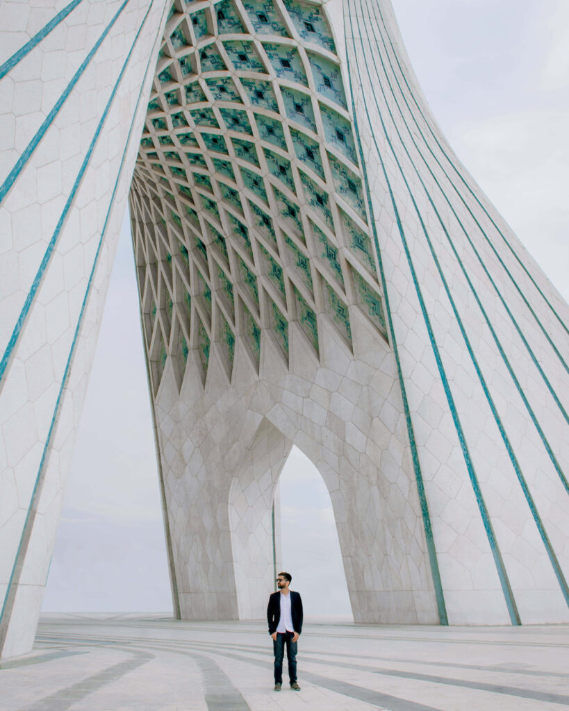 Man standing under Azadi Tower arches Tehran showcasing modern architecture cultural landmark Wallpaper