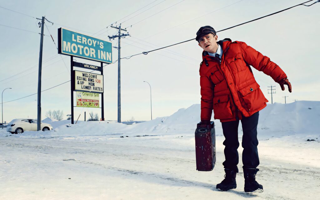Man in red jacket stands snowy landscape near Leroys Motor Inn Fargo series dramatic scene wallpaper