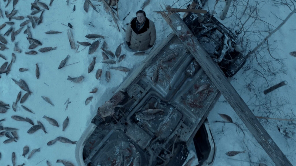 Man in snow beside overturned car and scattered frozen fish capturing Fargo surreal scene Wallpaper