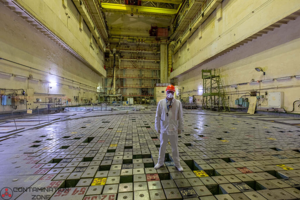 Man in protective suit inside Chernobyl reactor building surrounded by industrial machinery walls Wallpaper