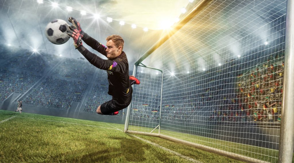Goalkeeper Manuel Neuer diving for a spectacular save in a packed stadium soccer wallpaper background