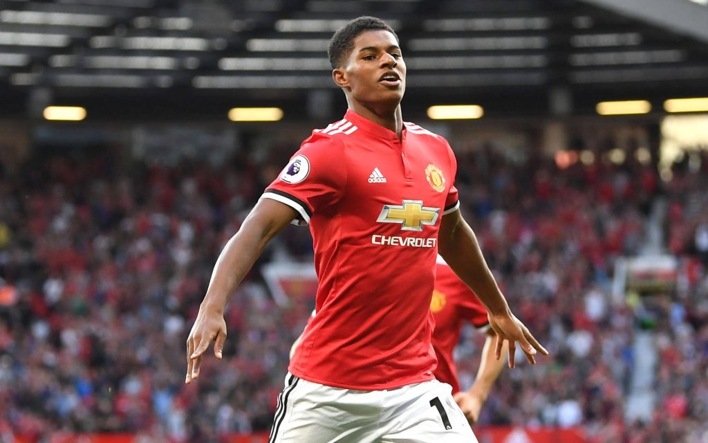 Marcus Rashford celebrating in Manchester United red kit with vibrant stadium background wallpaper