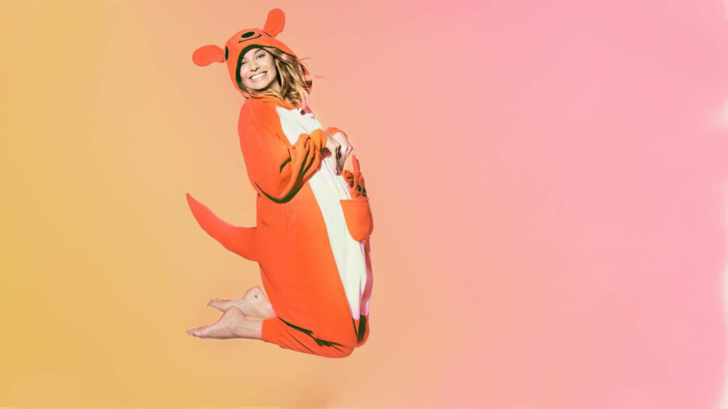 Margot Robbie jumping in playful kangaroo costume pink yellow gradient background wallpaper