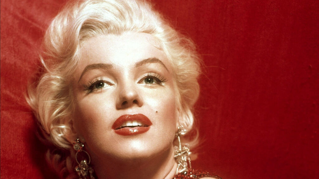 Marilyn Monroe with iconic red lips and glamorous style against rich red wallpaper background