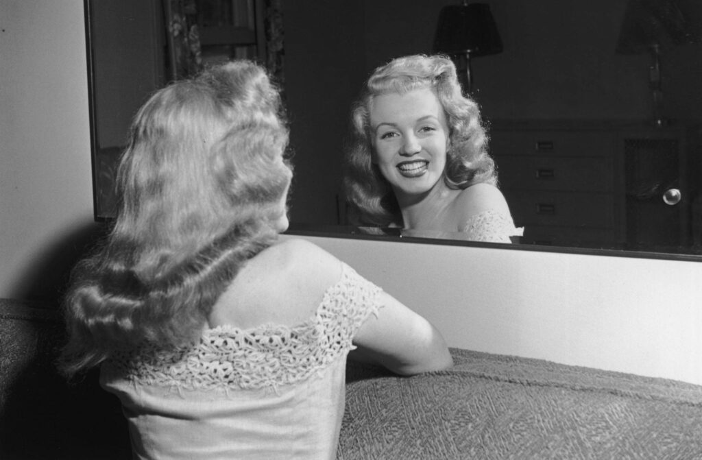 Marilyn Monroe smiling warmly at her reflection classic candid moment vintage wallpaper background