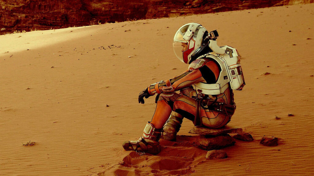Mark Watney in astronaut suit on Mars overlooking vast red desert symbolizing survival and exploration Wallpaper