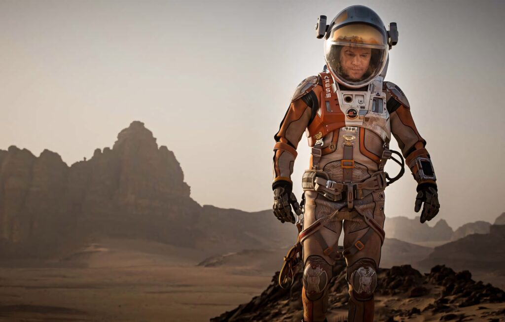 Mark Watney astronaut on Mars rugged rocky surface in space suit with mountains background wallpaper