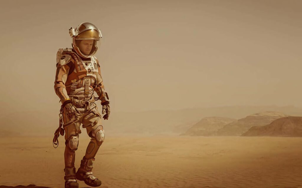 Mark Watney in spacesuit exploring barren Mars landscape showing isolation determination Wallpaper