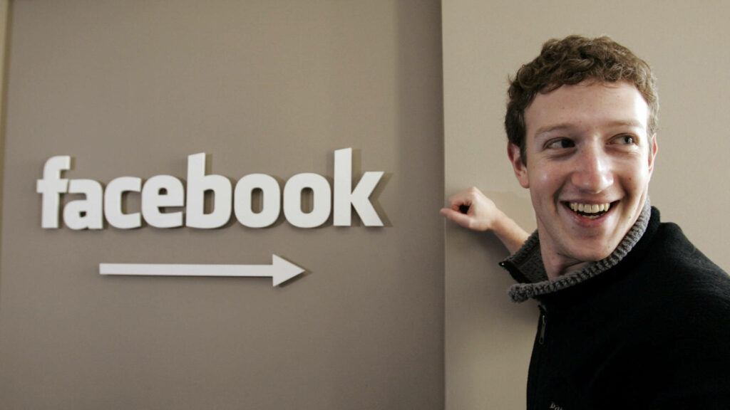 Cheerful Mark Zuckerberg Smiling by Facebook Logo - Joyful Wallpaper