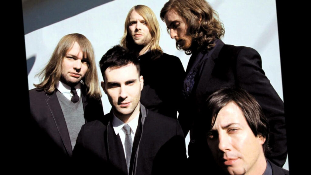 Maroon 5 band members posing stylishly together on bright vibrant wallpaper background