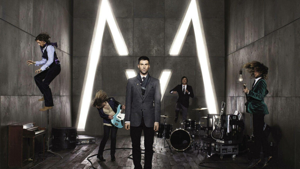 Maroon 5 band playing instruments in modern studio with glowing M wall for recording session Wallpaper