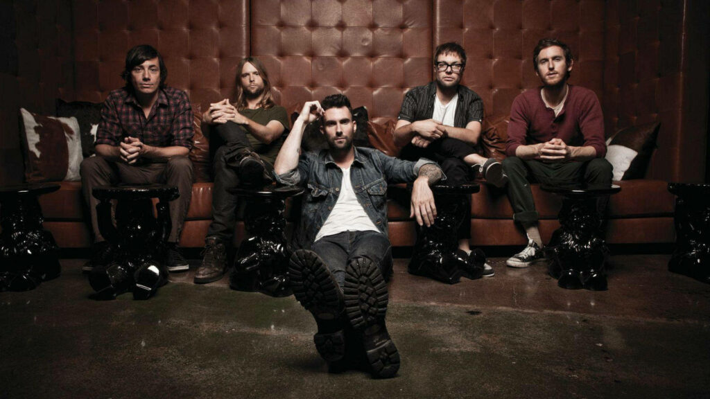Maroon 5 band members posing relaxed stylish in front of large brown leather sofa wallpaper background