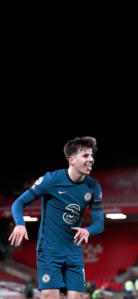 Mason Mount Chelsea FC midfielder celebrating with tongue out in blue kit stadium backdrop Wallpaper
