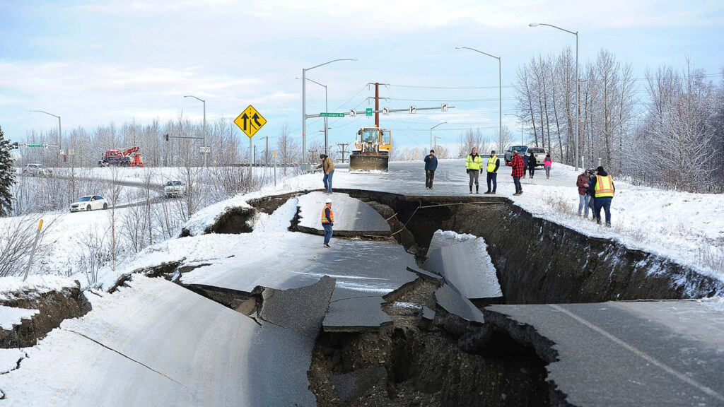 Massive earthquake cracks snow-covered road with workers and heavy machinery assessing damage winter Wallpaper