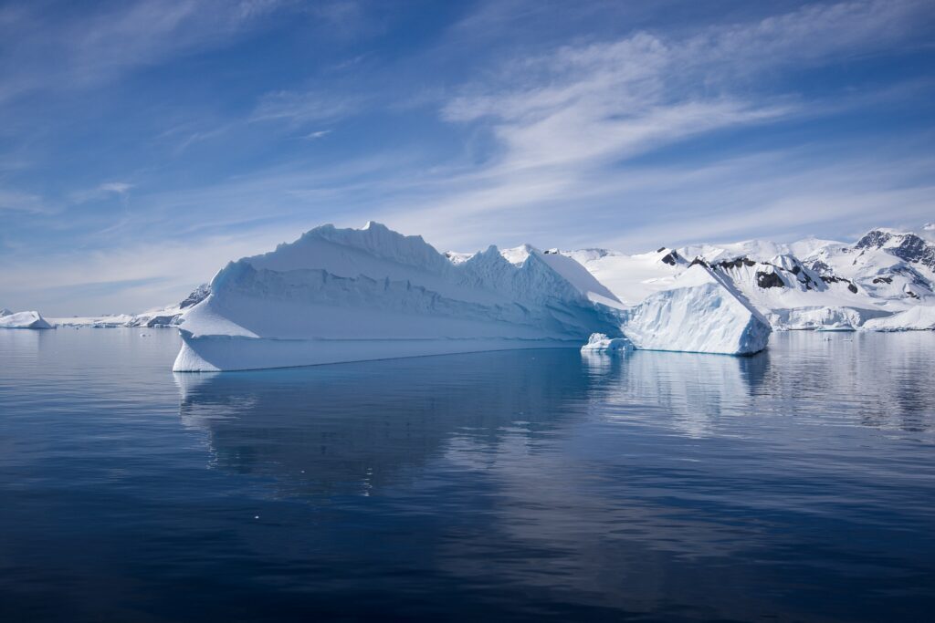 Massive iceberg in calm blue sea under dramatic sky photorealistic snowy icy landscape wallpaper