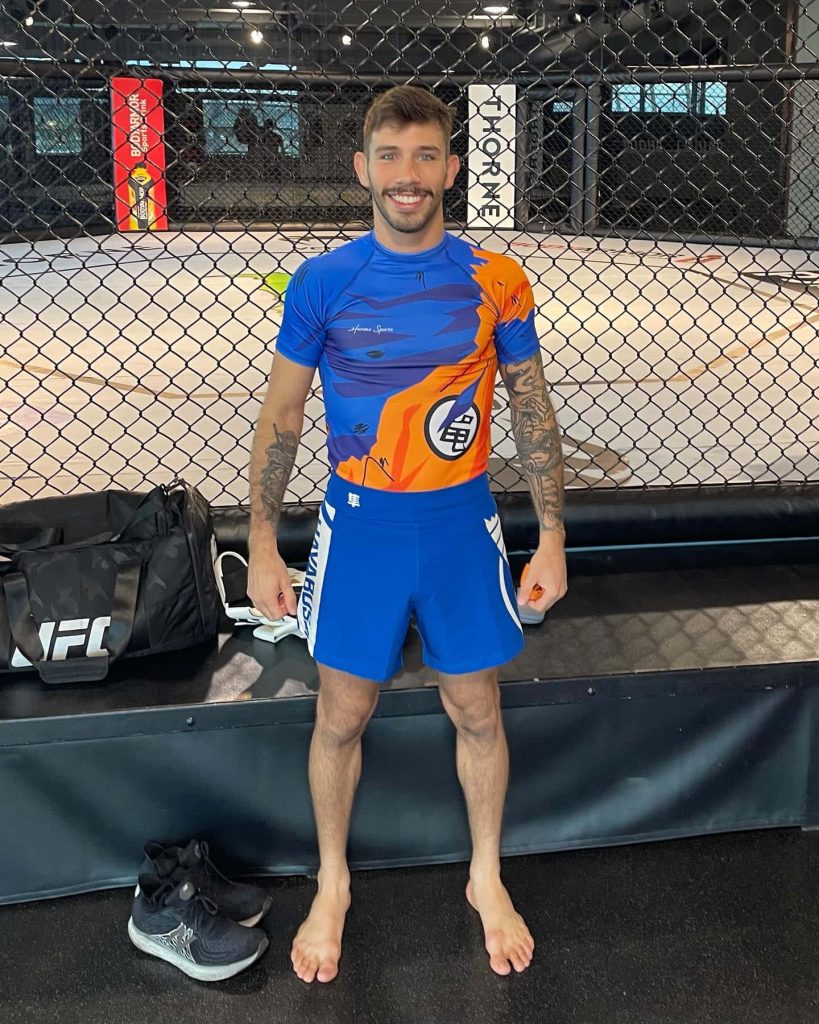 UFC fighter Matheus Nicolau in Dragon Ball Z compression gear posing in MMA gym background Wallpaper