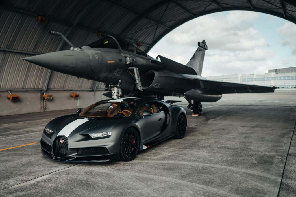 Matte black Bugatti Chiron parked in hangar with modern fighter jet luxury performance wallpaper