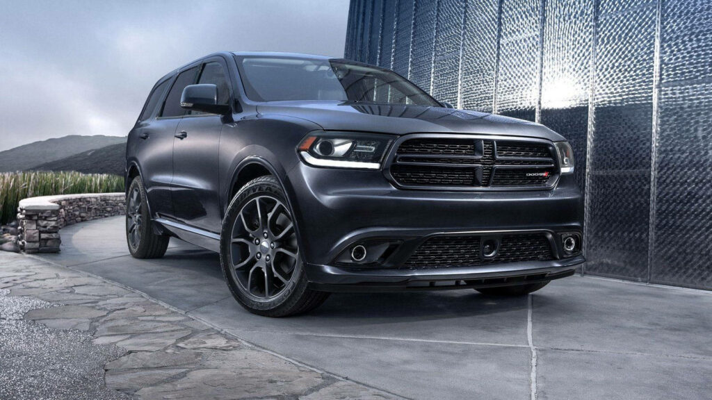 Matte black Dodge Durango parked by modern building showcasing bold design and power Wallpaper