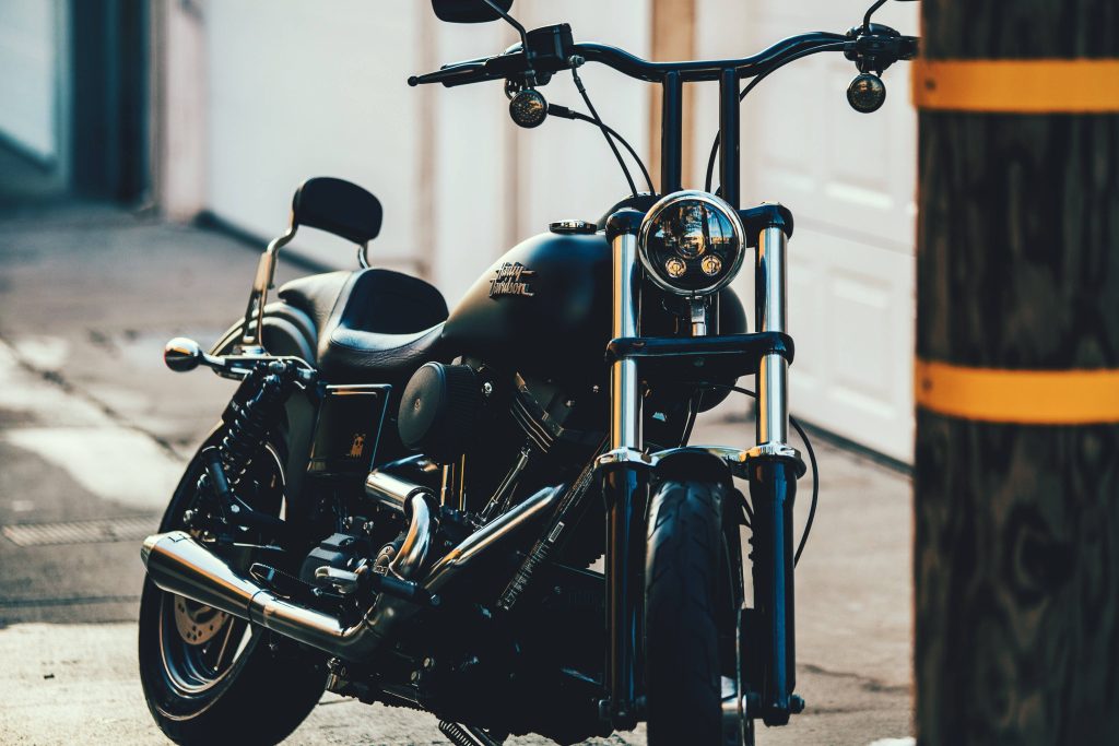 Matte black Harley-Davidson cruiser with tall handlebars and chrome exhaust front three-quarter view Wallpaper