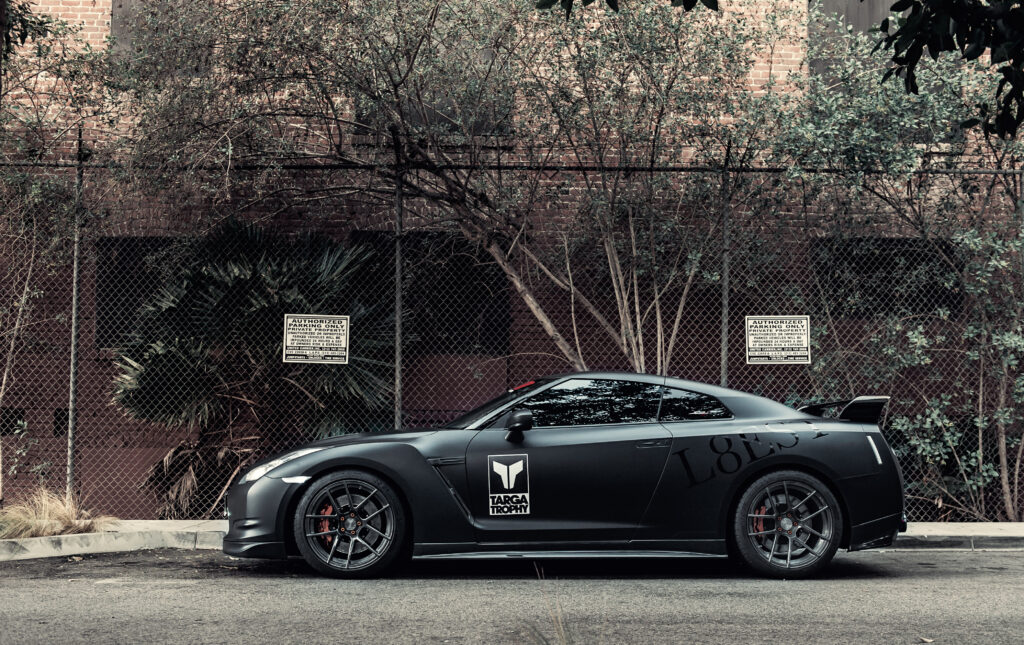 Sleek Matte Black Nissan GT-R: Sporty Design in Urban Greenery Wallpaper
