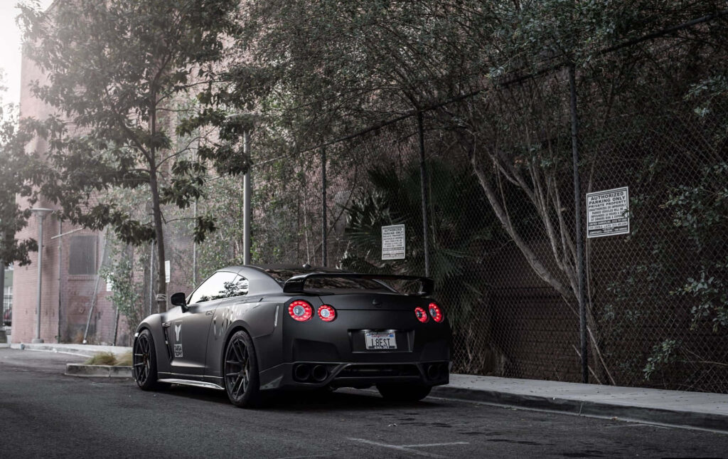 Matte black Nissan R35 GTR parked on urban street showcasing power style and sleek design Wallpaper