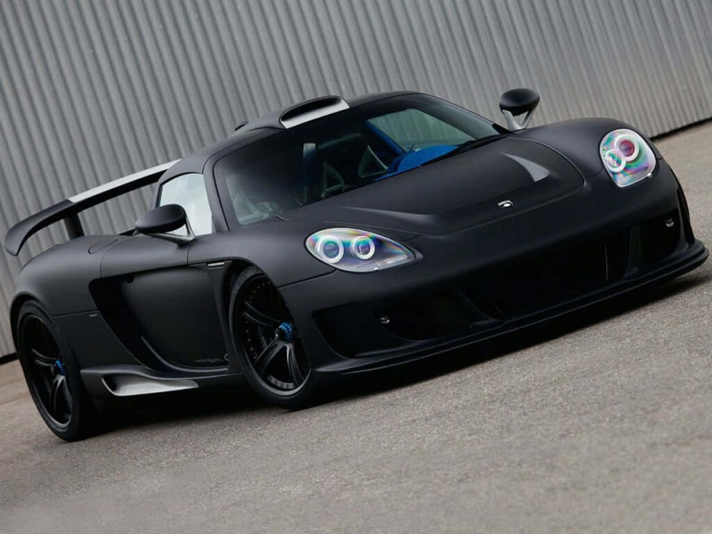 Matte black sports car with aerodynamic design parked by industrial building wallpaper background