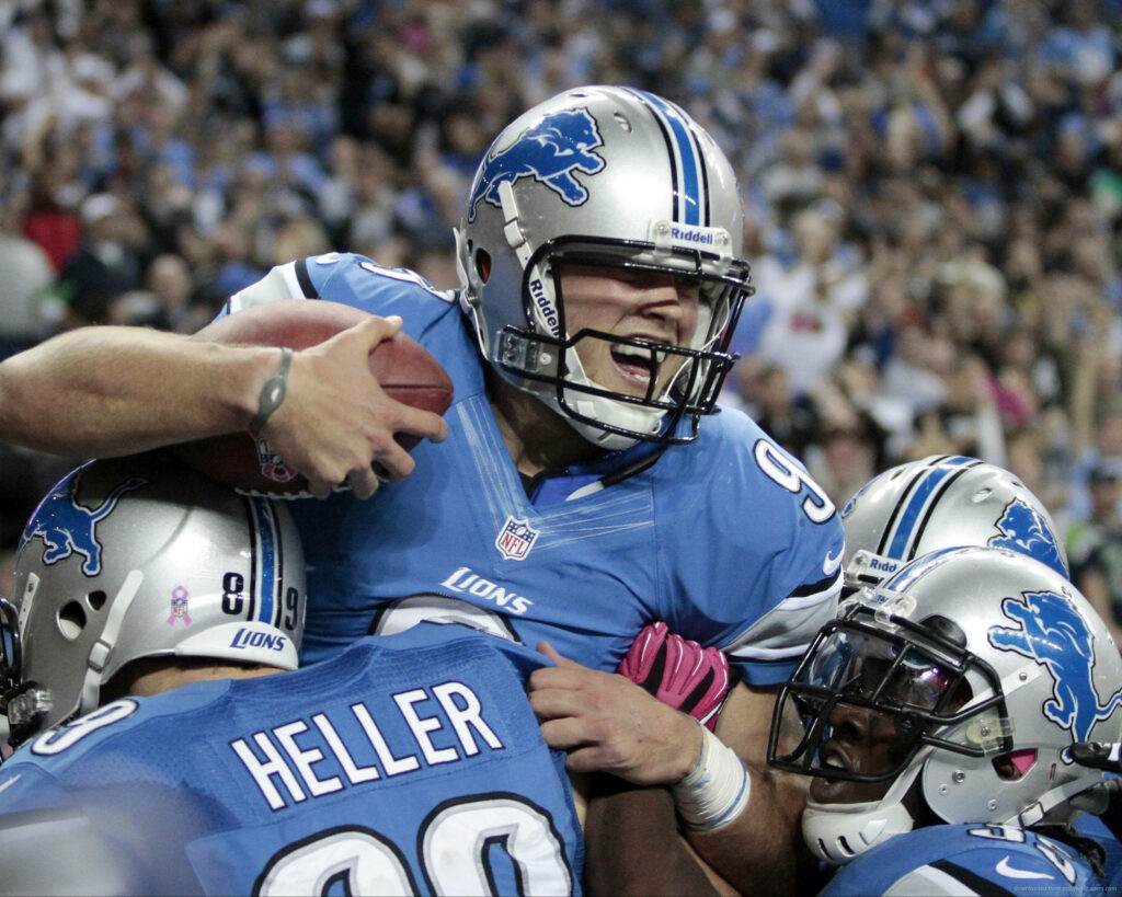 Matthew Stafford in Detroit Lions jersey celebrates with teammates during intense NFL game action Wallpaper