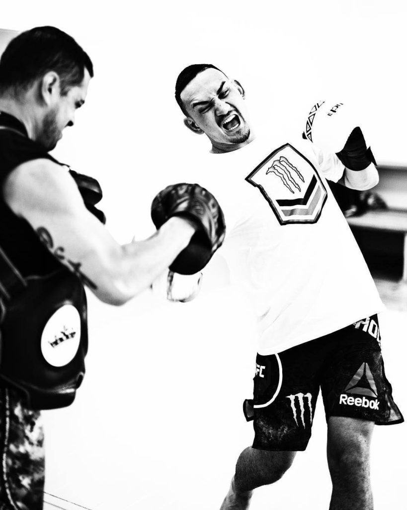 Black and white UFC wallpaper Max Holloway training punching focus mitts Reebok fight gear