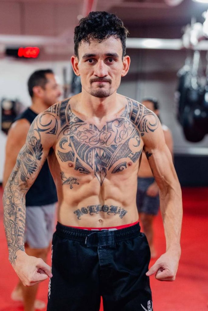 High-definition wallpaper of UFC star Max Holloway training with tribal tattoos in gym