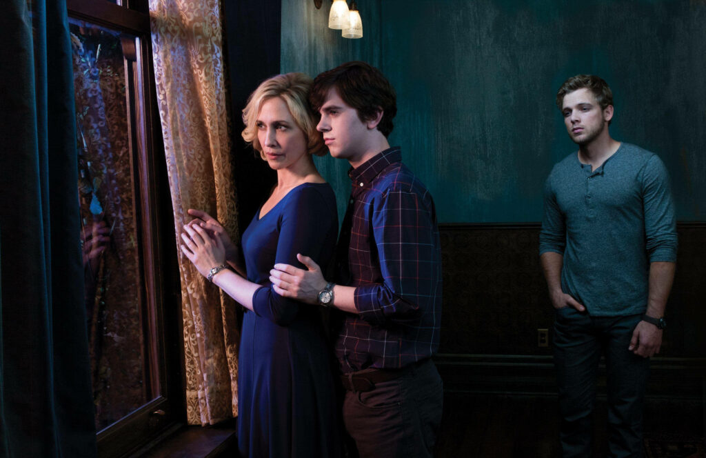 Max Thieriot with Bates Motel cast in intense suspenseful scene dimly lit room wallpaper background
