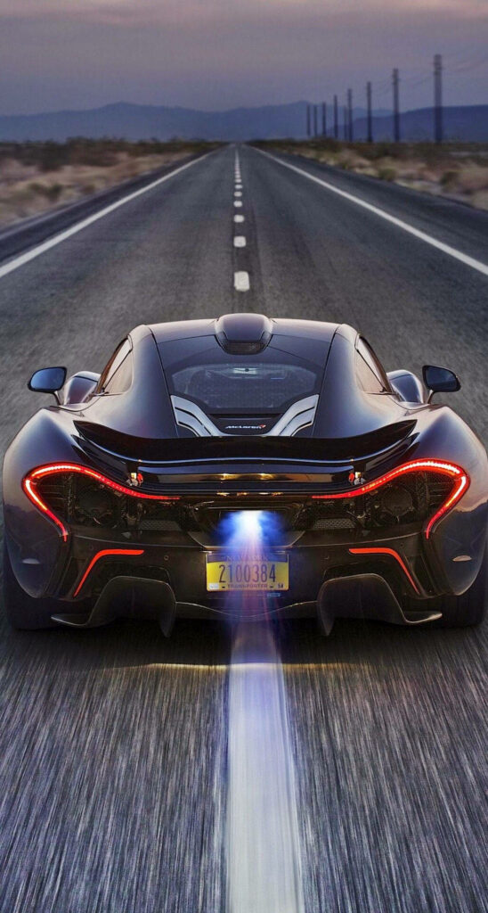 Rear view of sleek McLaren P1 speeding on desert highway showcasing futuristic design and power Wallpaper