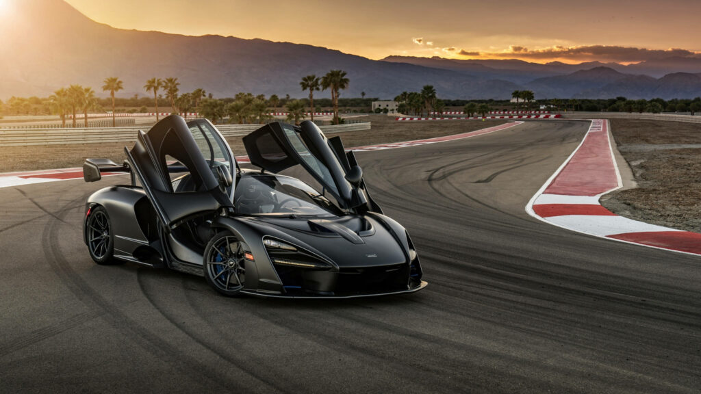 McLaren Senna with open dihedral doors on racetrack sunset mountains palm trees wallpaper
