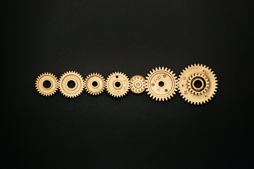 Mechanical gold gears in a horizontal row on black background industrial wallpaper design