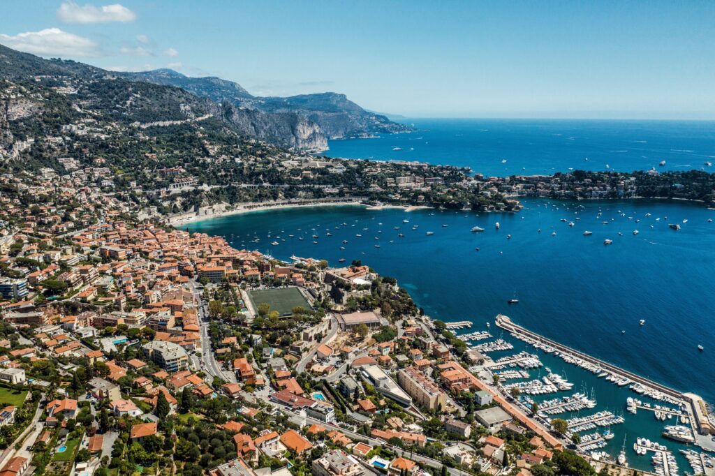 Coastal city with terracotta rooftops boats marina rocky hills blue sea Mediterranean wallpaper