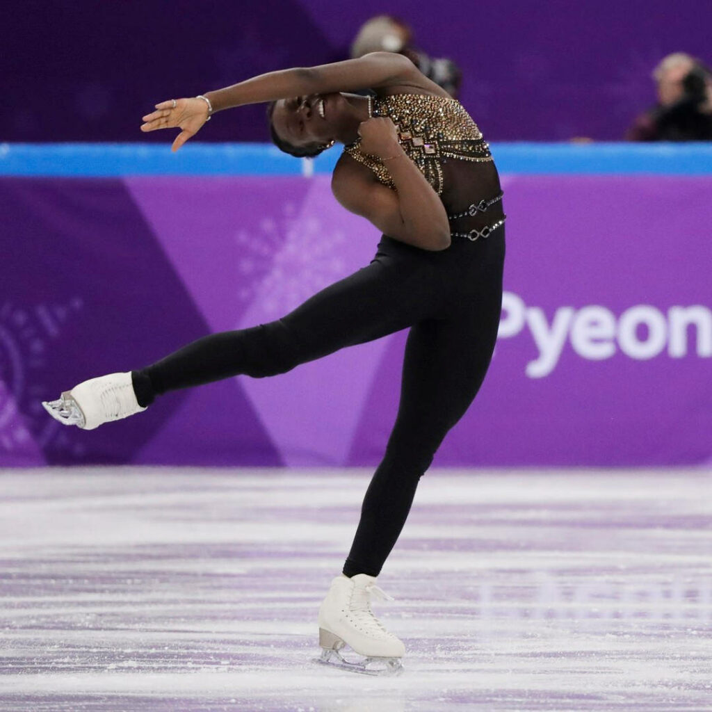 Meite striking an elegant figure skating pose on ice at 2018 Winter Olympics purple backdrop wallpaper