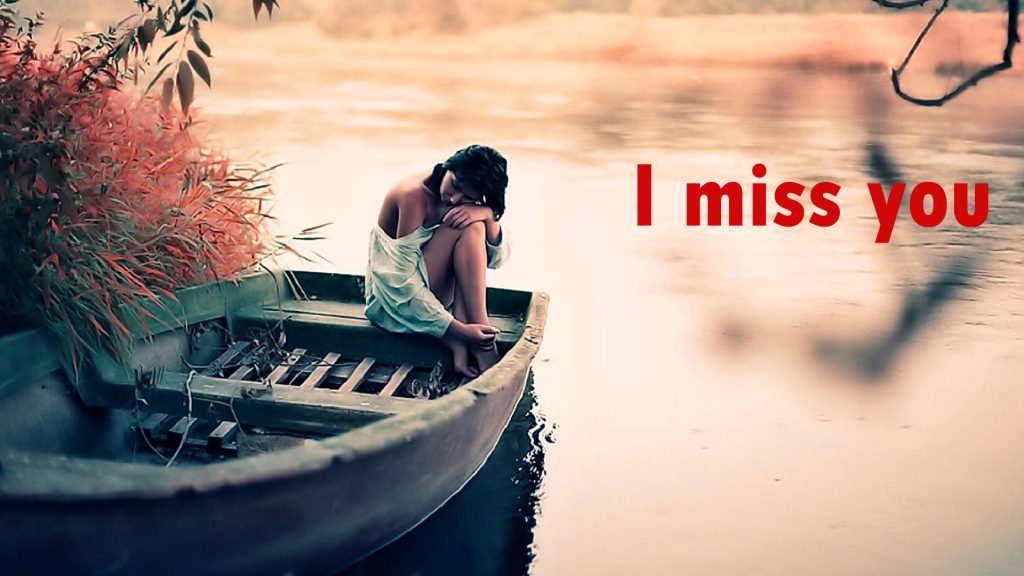 Melancholic woman seated in rustic boat on calm water with red I miss you text romantic wallpaper