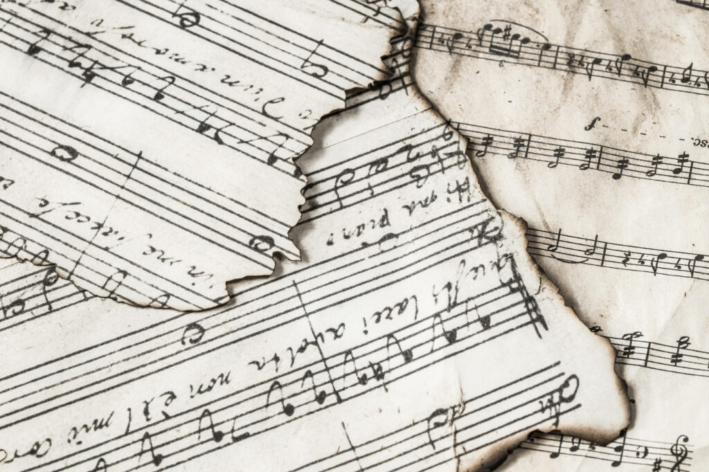 Melodious Ephemera: 4k Wallpaper Showcasing Singed and Tattered Sheets of Music