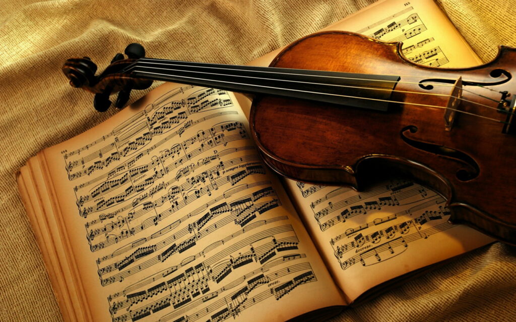 Polished wooden violin on vintage sheet music with warm golden lighting and rustic fabric background Wallpaper