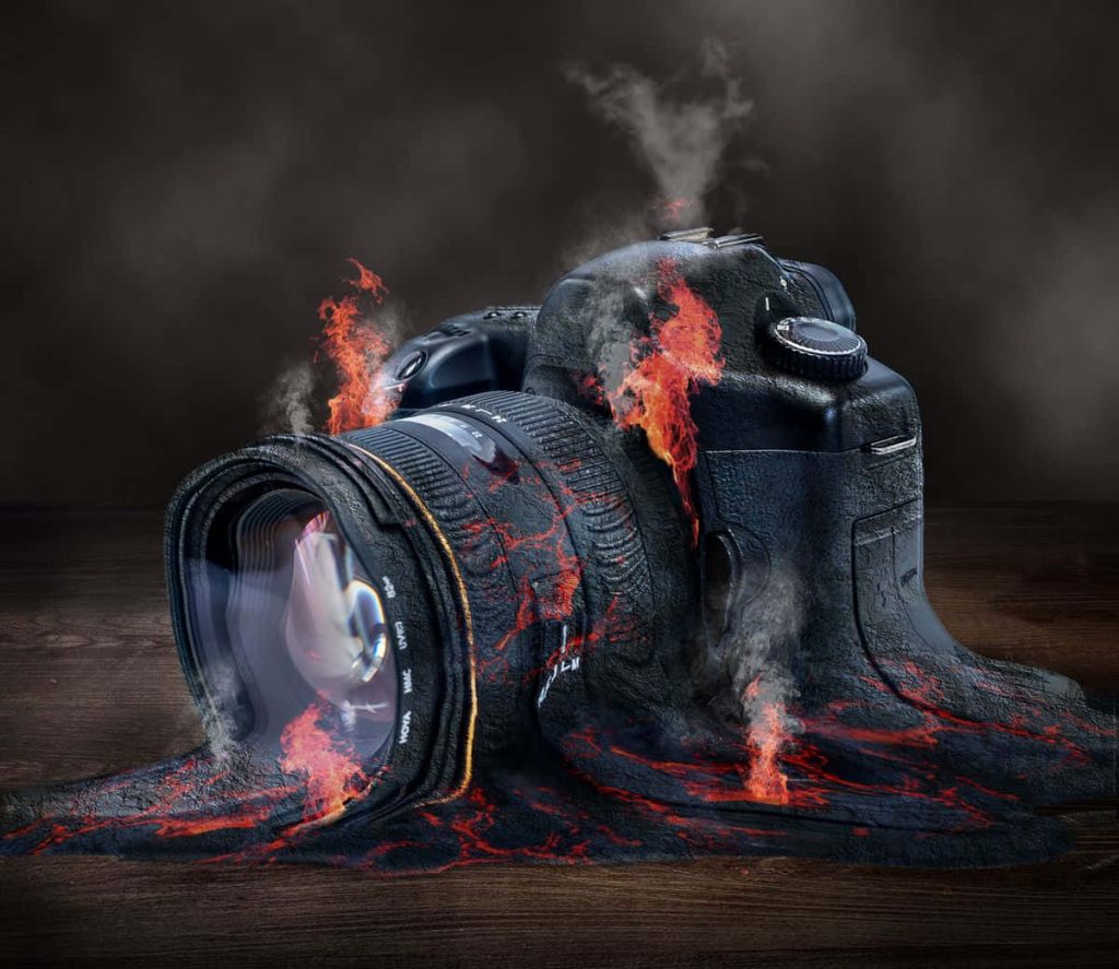 DSLR camera melting into lava flames on wood creative digital art wallpaper background