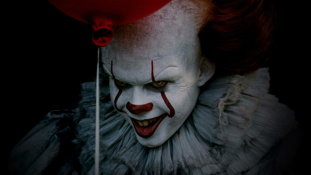 Menacing Grin: Pennywise From 'It' Wallpaper with Red Balloon in the Dark