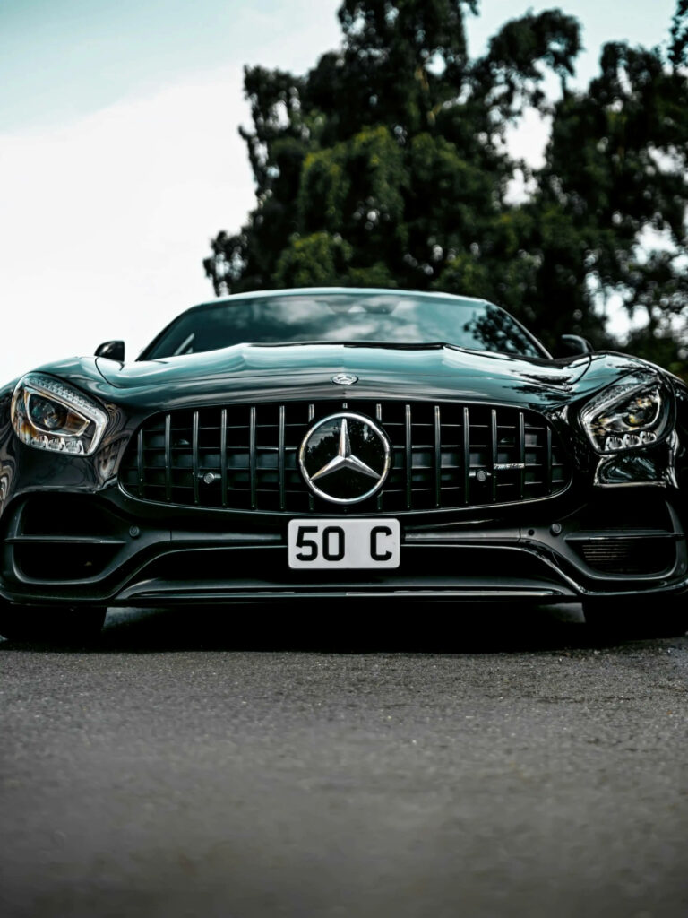 Front view of gleaming Mercedes AMG with bold grille and headlights in natural outdoor setting Wallpaper