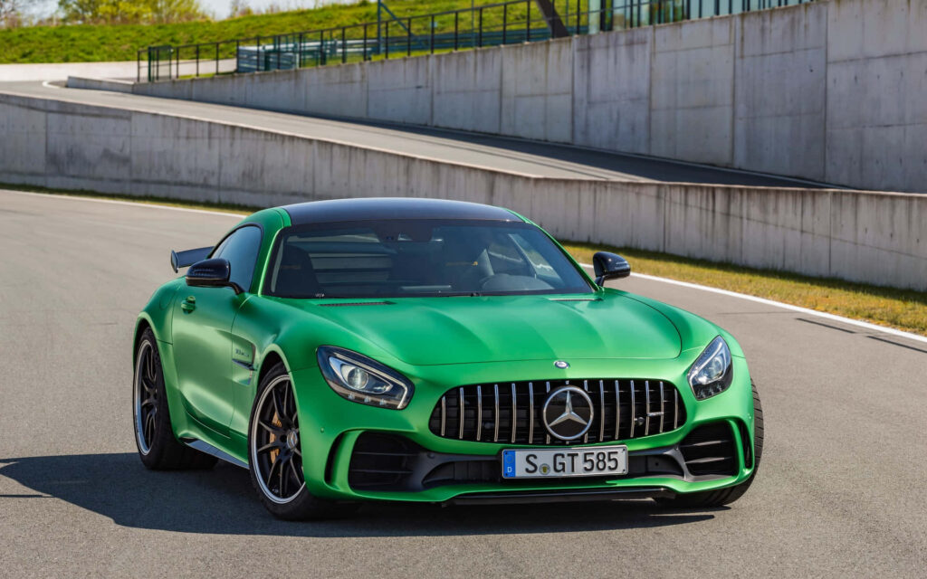 Vibrant green Mercedes AMG GT-R on racetrack showcasing sleek design and aggressive grille Wallpaper