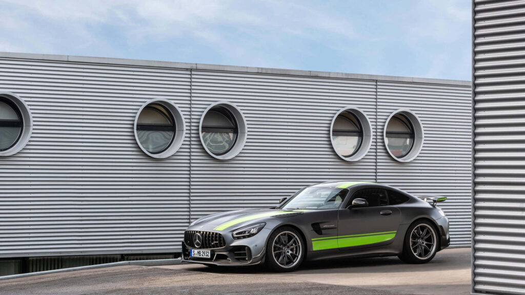 Mercedes AMG GT R with green racing stripes parked by modern industrial building wallpaper background