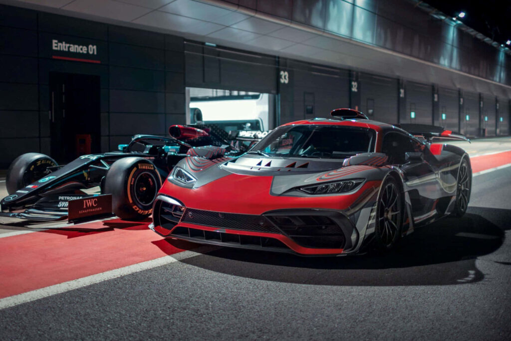 Mercedes AMG hypercar and sleek Formula 1 car showcased on racetrack under artificial lights wallpaper