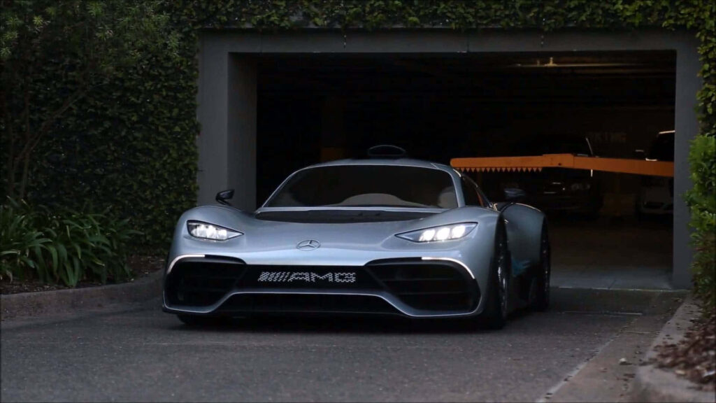 Mercedes AMG hypercar in modern garage surrounded by lush greenery and stylish outdoor setting Wallpaper