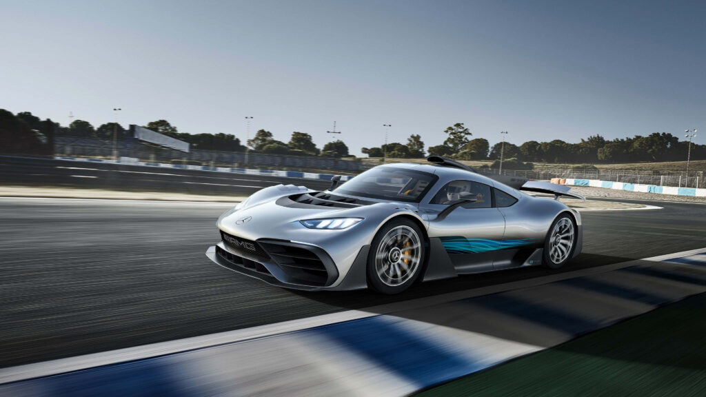Mercedes AMG racing on track under clear sky showcasing aerodynamic design and high performance Wallpaper
