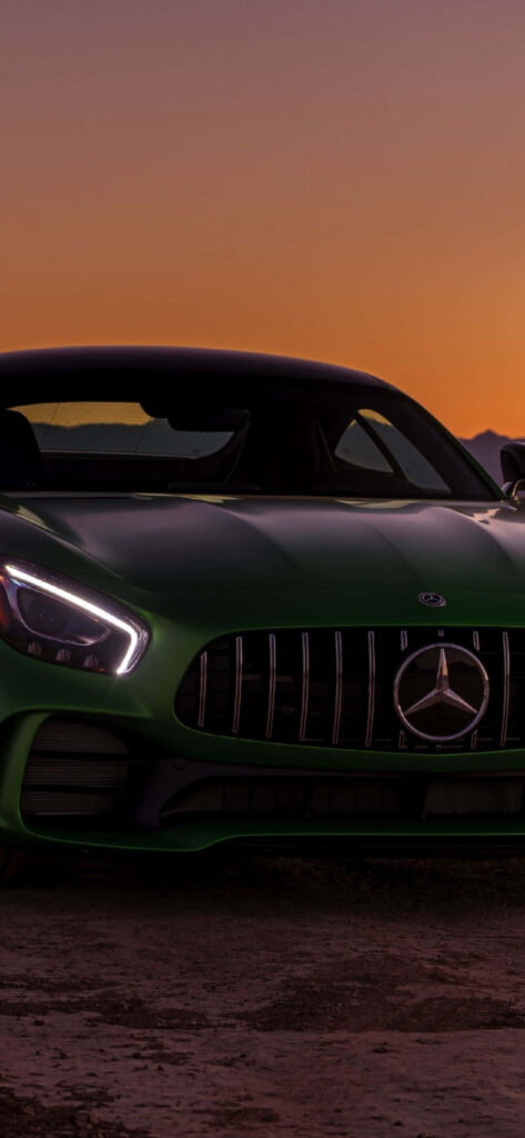 Dark grey Mercedes-Benz AMG GT with sleek lines and AMG grille at vibrant sunset wallpaper background