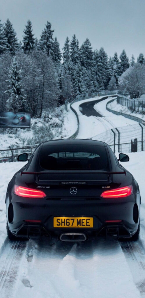 Mercedes-Benz AMG GT-R black sports car on snowy forest road with sleek design wallpaper background